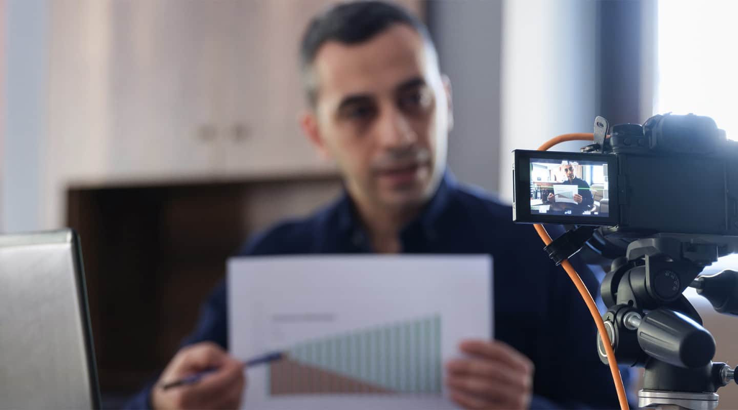 Finfluencer man recording a video while pointing at a chart